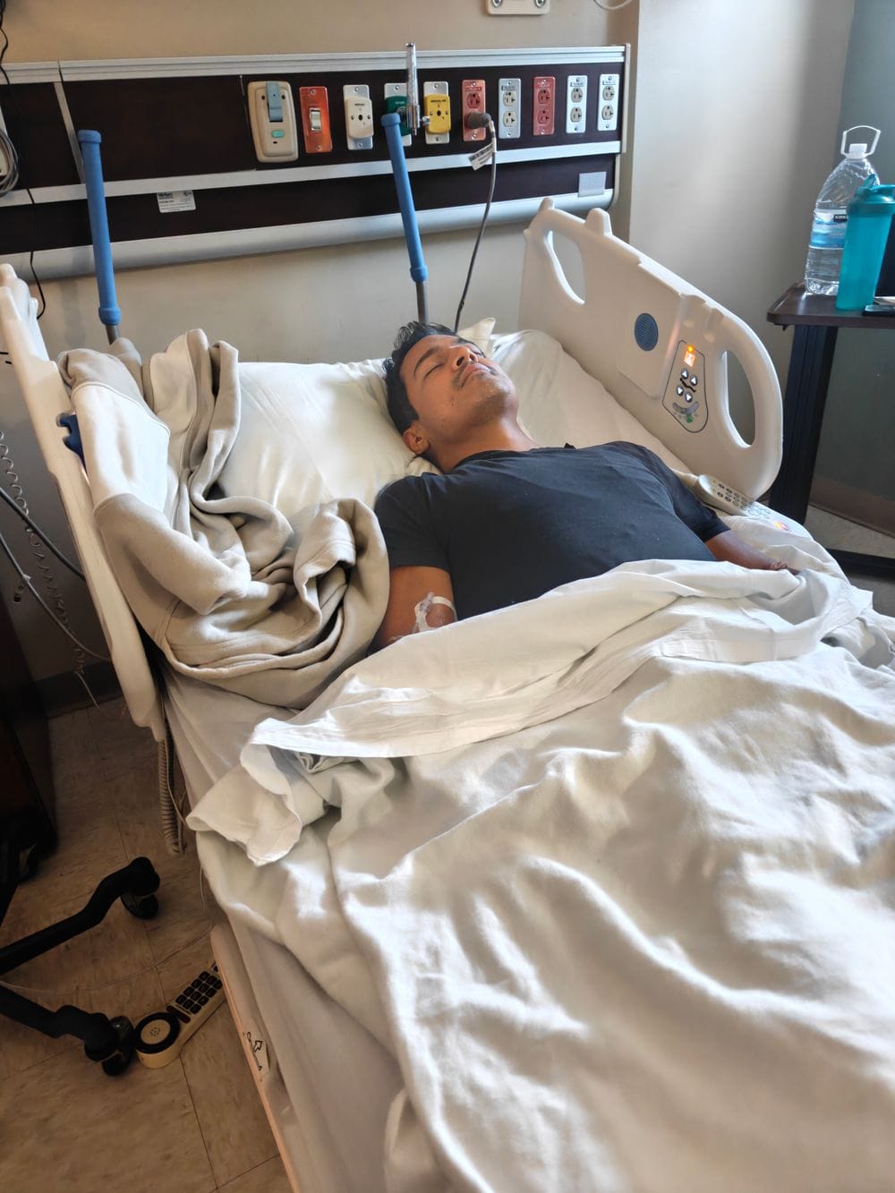 Karamat asleep in a hospital bed after being readmitted to Delray Medical Center, June 2026